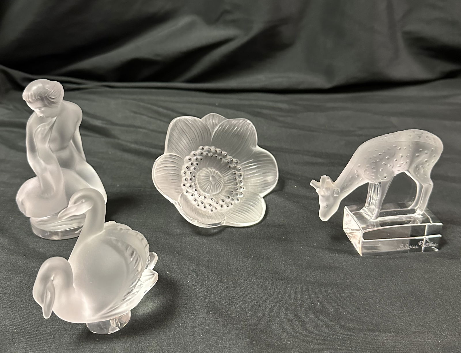 Four Lalique Figural Pieces - II: Group of four figural Lalique pieces including a nude with a goose, a deer, a pair of swans and an Anemone flower paperweight.