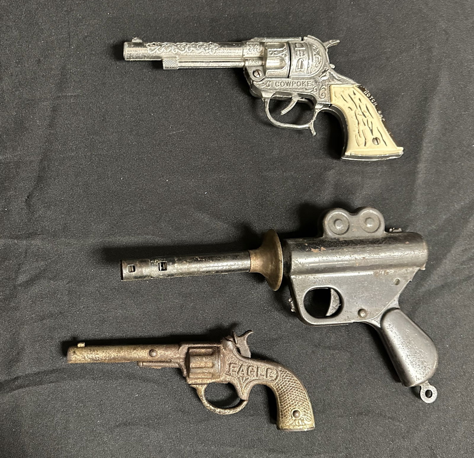 Group of Three Vinage/Antique Toy Pistols: Three vintage / antique toy pistols including an Eagle 1890 cast iron cap gun, a 1935 Daisy Buck Rogers pistol called Wilmas Gun and a Hubly 1950s Cowpoke Cap Gun with a Notch Bar on the handle.