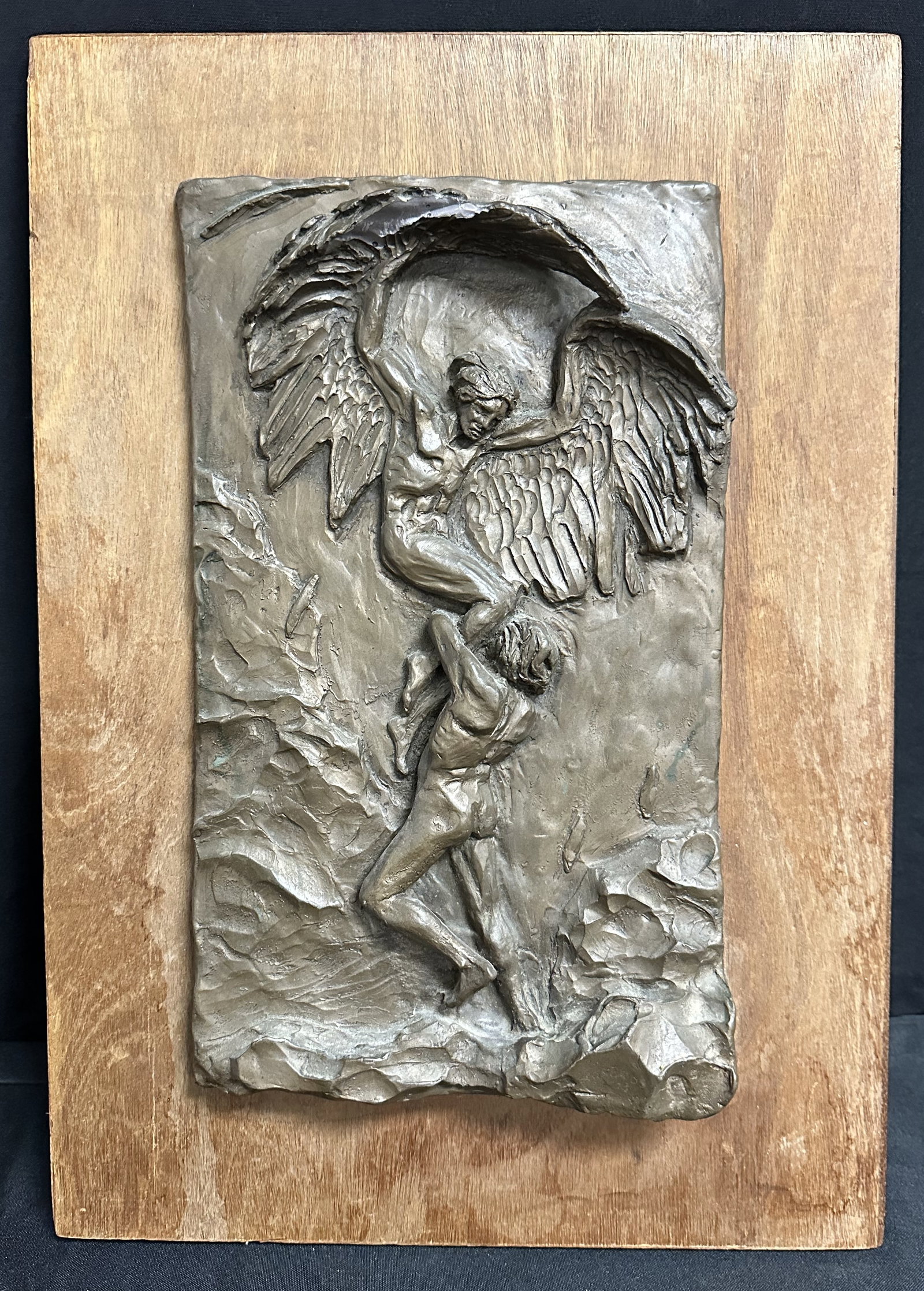 Plaque by Economos - Greek Mythology: Metal plaque mounted on wood of a mythological scene signed ECONOMOS. Plaque shows a winged man struggling to stay in the air as someone grabs his legs. Forgive me for not being up on my Greek Mytholo