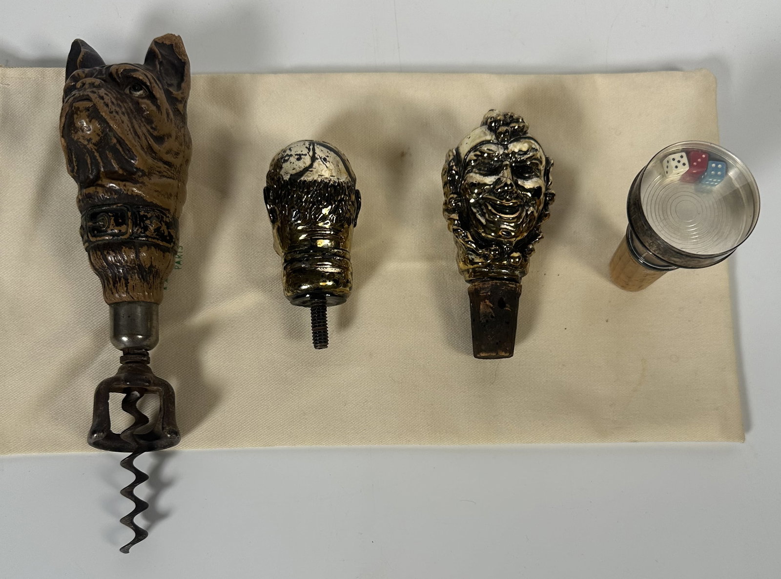 RR Four Pieces Vintage Barware Group: Four Pieces Vintage Barware Group An assembled group of four vintage barware pieces featuring one dog head corkscrew and three interesting corks. Most unique is the cork with three dice under