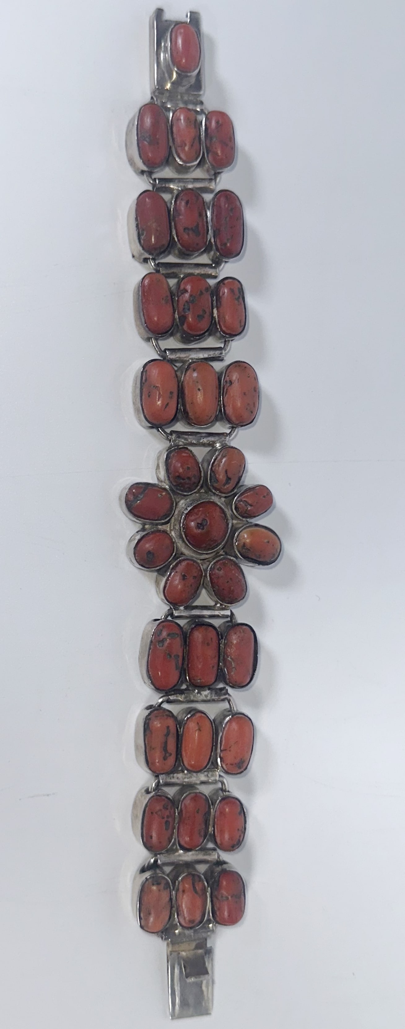 Sterling Silver and Coral Bracelet Native American: Sterling Silver and Coral Bracelet Native American Eight inch long silver bracelet with coral insets forming a flower at its center. Marked 925 on the back. Likely over 40 years old done in the Native