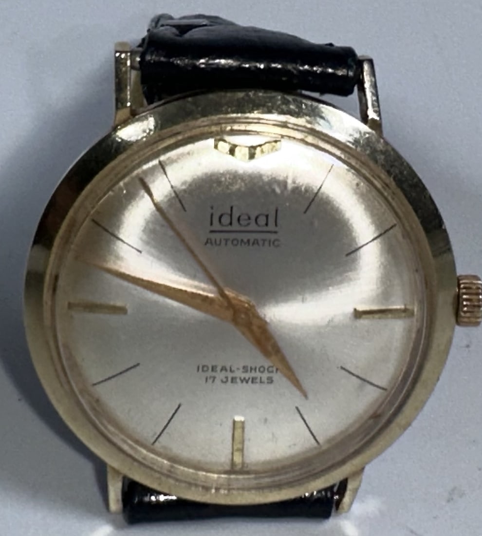 Vintage 14k Yellow Gold Automatic Watch 17 Jewels Ideal: Vintage 14k Yellow Gold Automatic Watch 17 Jewels Ideal This is a vintage Ideal Automatic wristwatch featuring a round gold-tone case, a sunburst silver dial with stylized dagger hands, and a black le