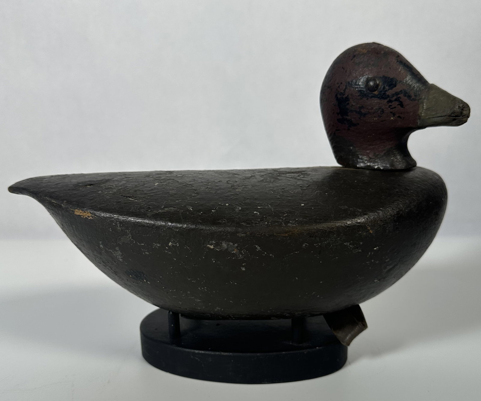Vintage Hand Carved Duck Decoy on Stand: Vintage Hand Carved Duck Decoy on Stand This object is a vintage hand-carved and painted wooden duck decoy, featuring a dark body and a reddish-brown head mounted on a custom display stand. Folk-art s