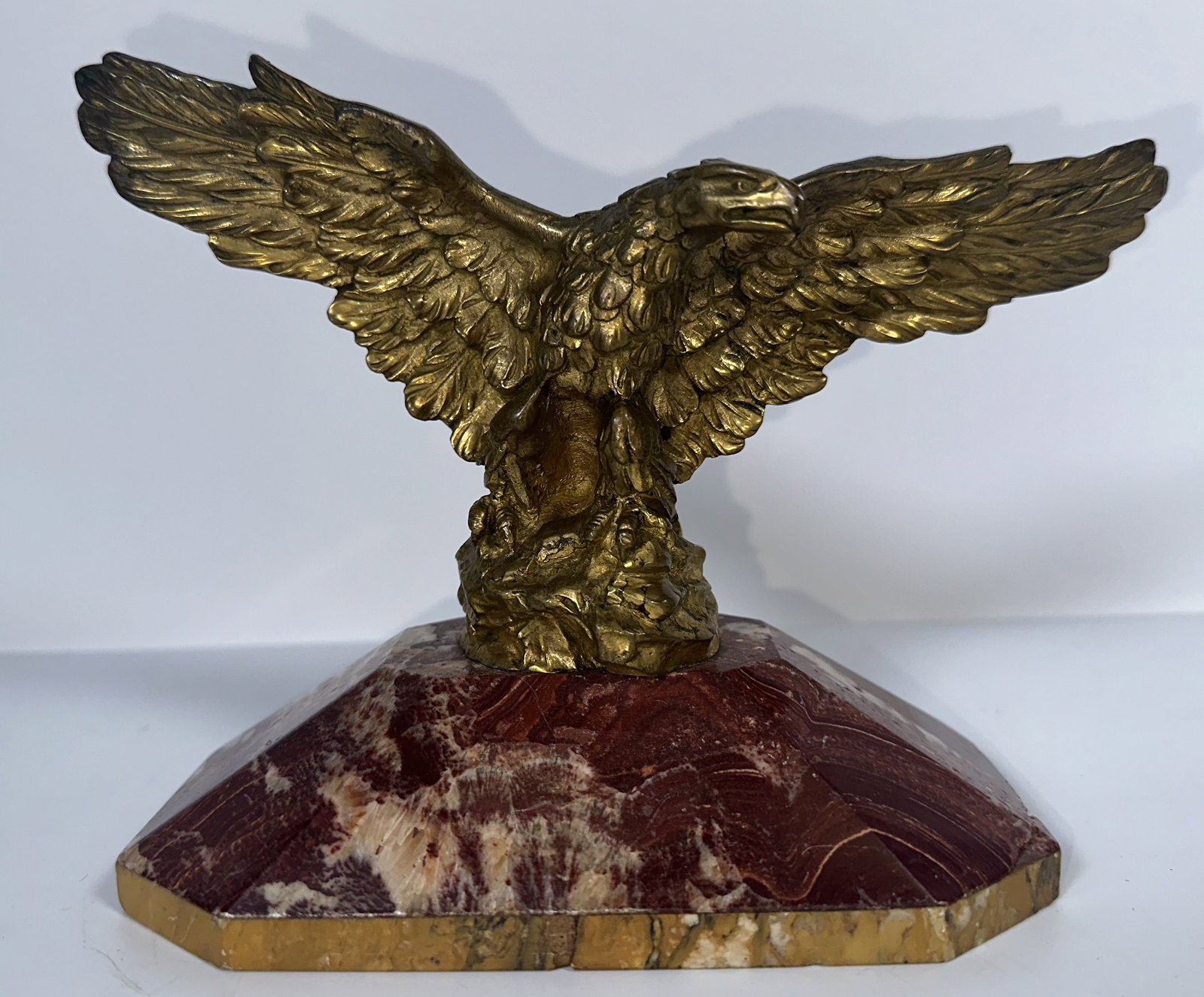 Gilt Metal Eagle on Stone Base: Gilt Metal Eagle on Stone Base A decorative gilt metal eagle on stone desk object. Well detailed on fine red marble. For this lot shipping can be done one of two ways: In-House Shipping - A Shipping Q