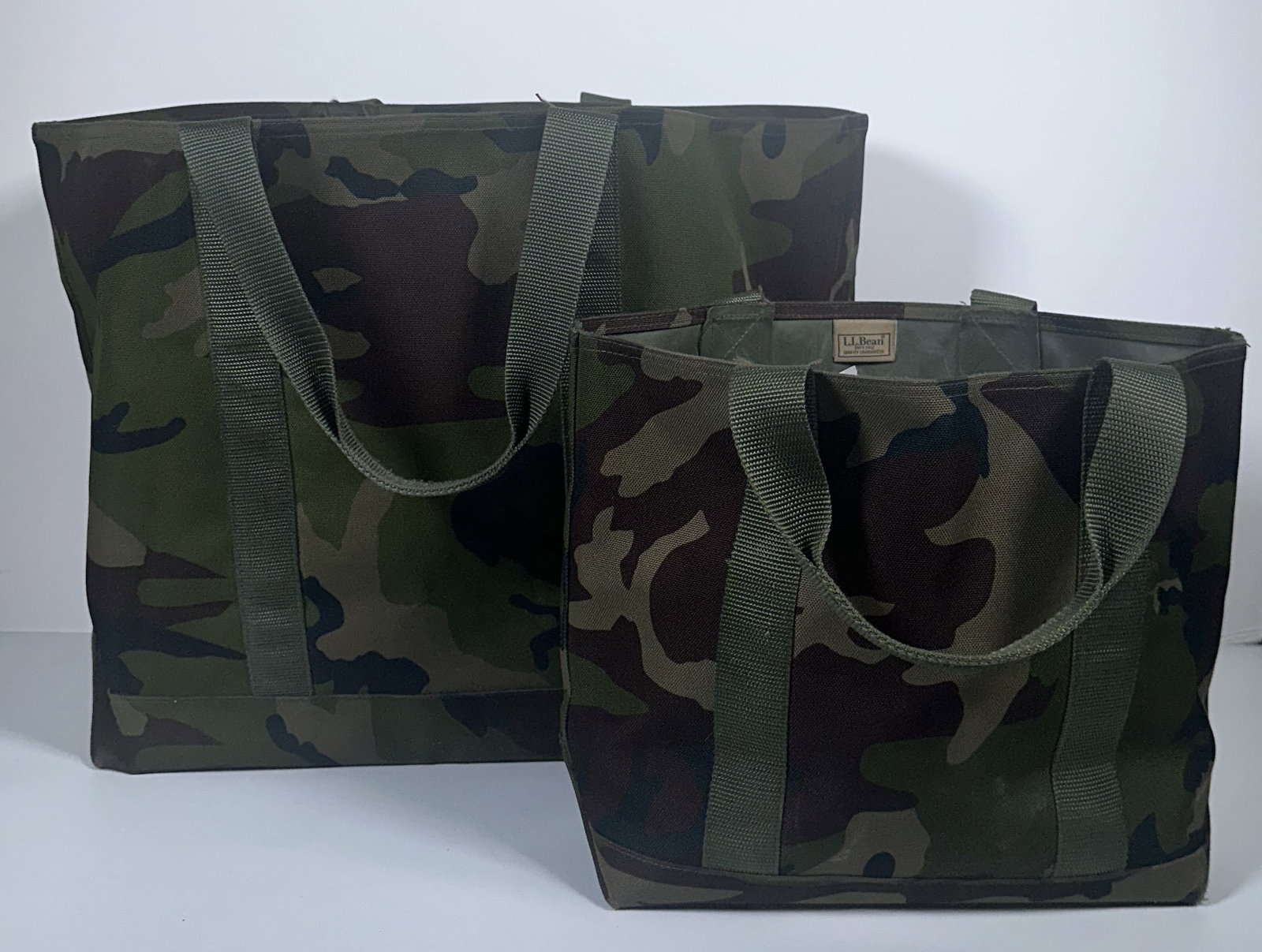 Two Large Hunters Tote Bags by LL Bean: Two Large Hunters Tote Bags by LL Bean This lot includes two large L.L.Bean Hunters Totes features a durable woodland camouflage nylon shell with olive green webbing handles. Please see photos for