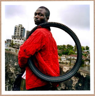 ESTATE STAMPED - TIM HETHERINGTON BOY WITH A FIRESTONE TIRE - LTD 6" x 6" MAGNUM ARCHIVAL PRINT.: Description: 6"x 6" limited edition Fuji Crystal Archival Matte paper print. Image size is 5.5" on the longest side and the paper size is 6" x 6". The Print is ESTATE STAMPED on the verso.Condition: B