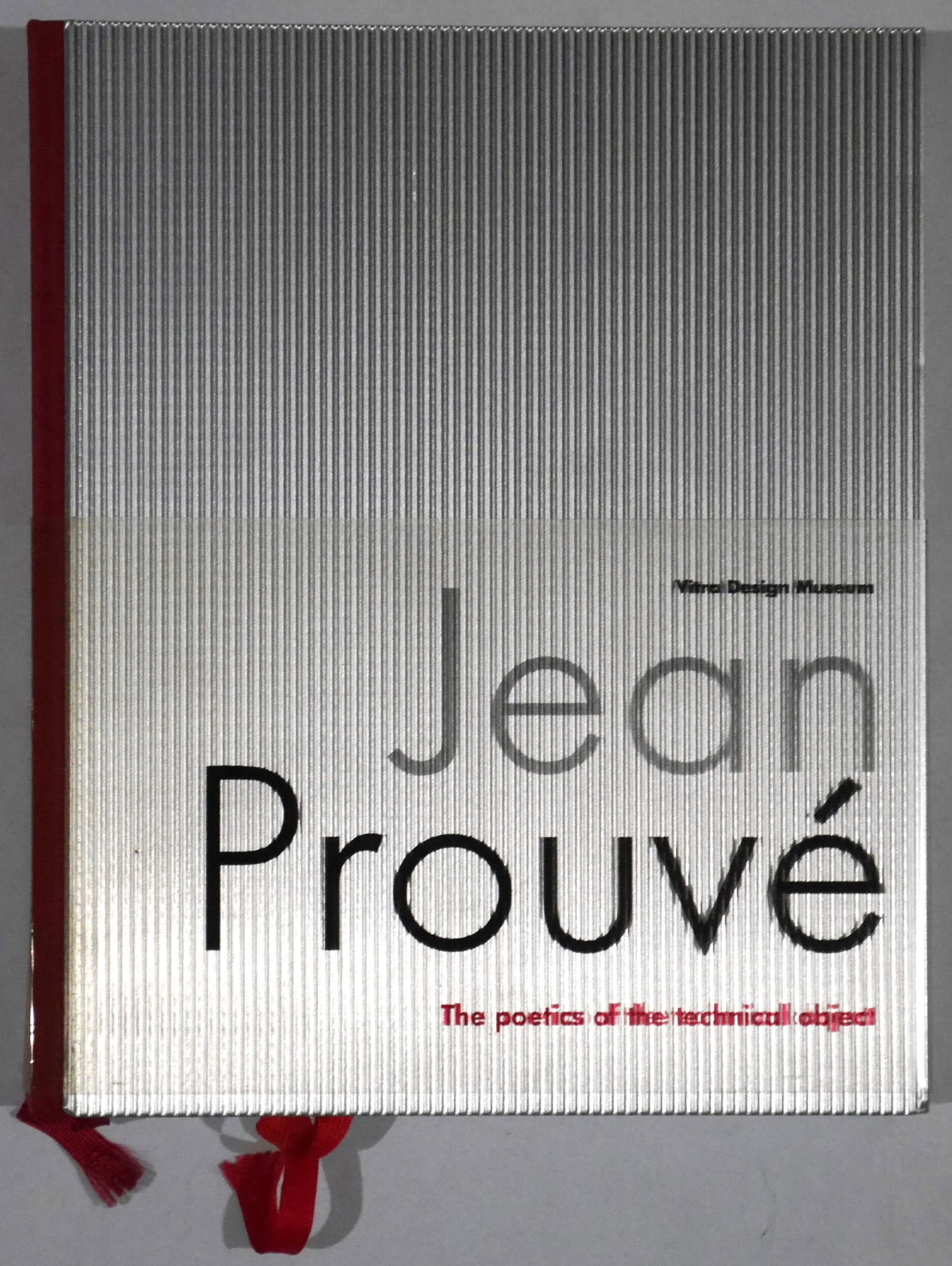 Prouve, Jean; Jean Prouve, The Poetics of the Technical Object [2005 1ST EDITION WITH BELLY BAND -: Vitra Design Museum, 2005. Hardcover with corrugated aluminium covered boards and the printed acetate belly band (with several satin bookmarks bound in - as issued). First Edition, First Printing. Lar