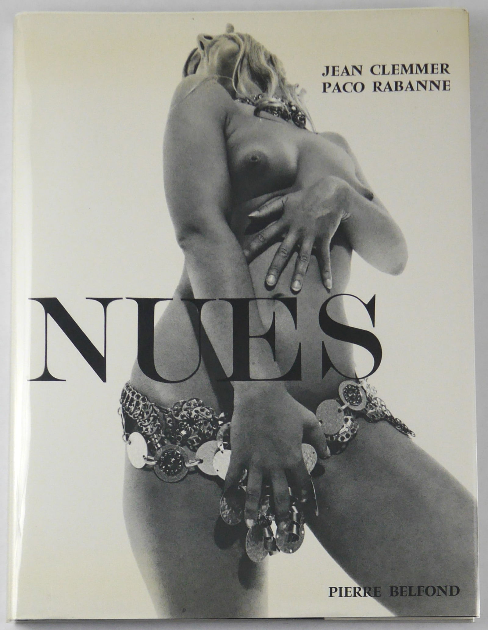 Rabanne, Paco & Clemmer, Jean; Nues [WITH DUST JACKET & ORIGINAL CLEAR ACETATE COVER - FINE COPY]: Editions Pierre Belfond, Paris, 1969. Hardcover in dust jacket and clear acetate cover. First Edtion, First Printing. Photographs by Jean Clemmer. Designs & text by Paco Rabanne (text in French). 84 p