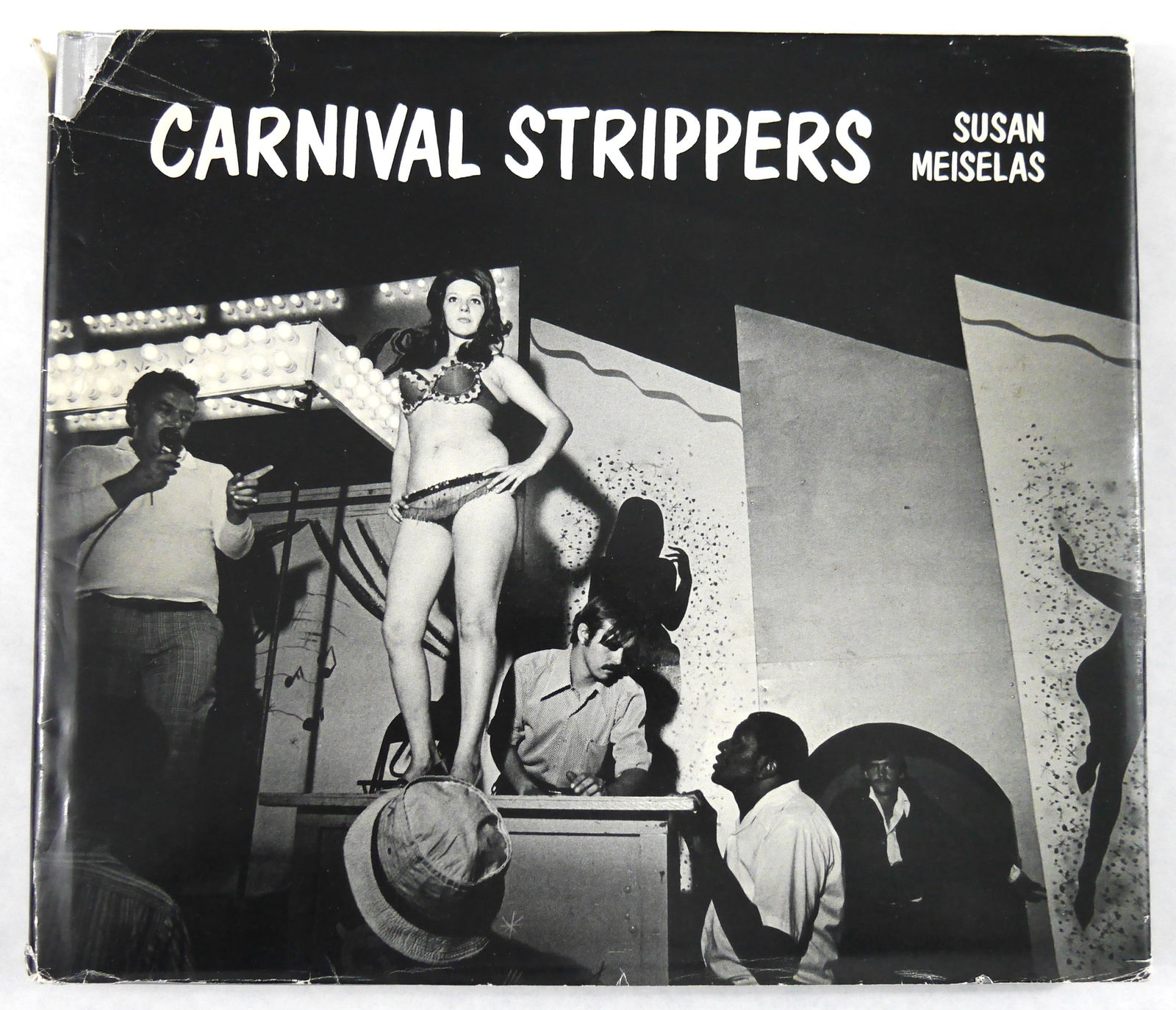 Meiselas,Susan; Carnival Strippers [1976 1ST EDITION & 1ST PRINTING HARDCOVER WITH DUST JACKET -: Farrar, Straus and Giroux 1976. Hardcover in silver/grey boards in pictorial dust jacket. First Edition, First Printing. Size: 8vo - over 7¾" - 9¾" tall. 150 pages with numerous black an