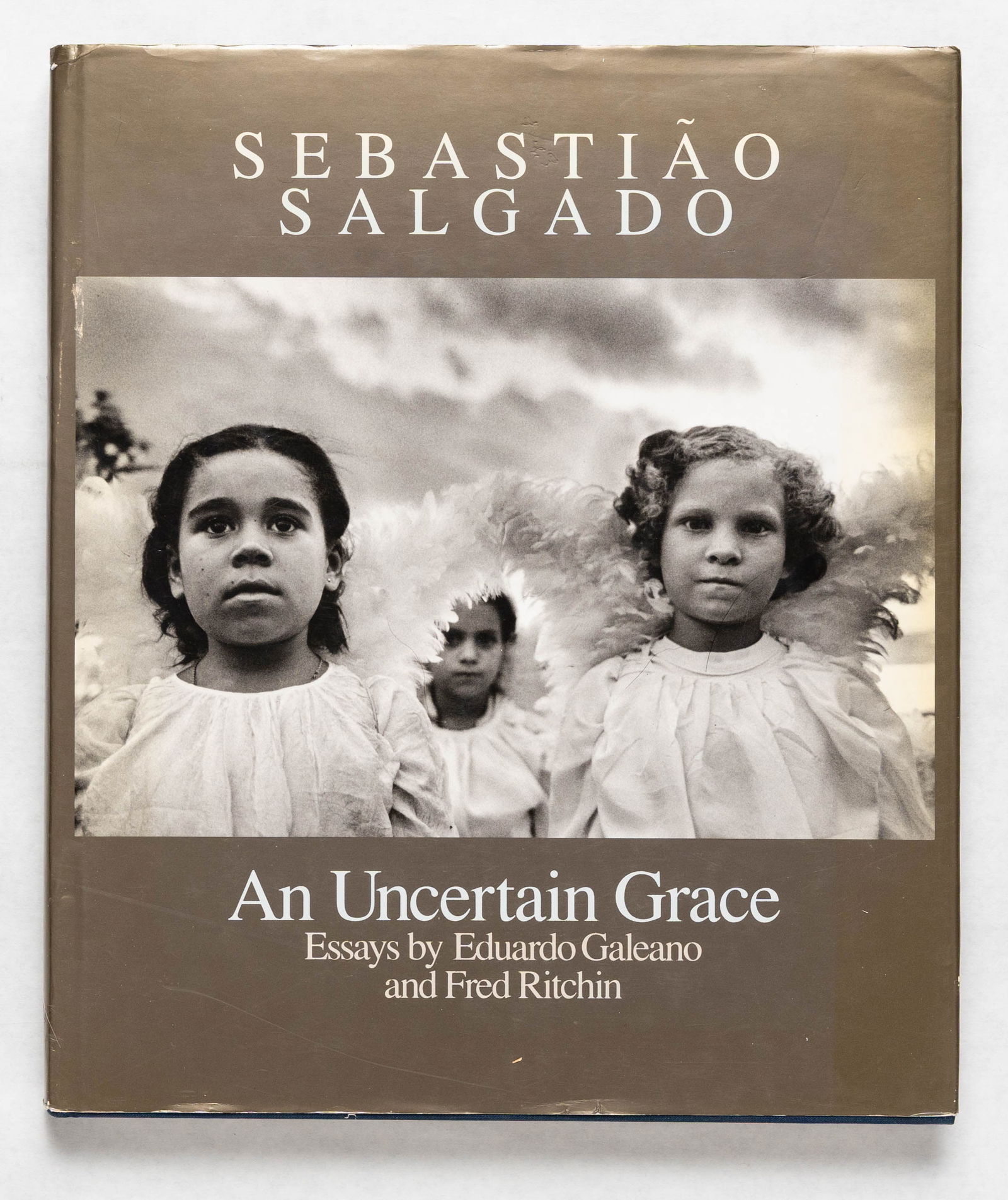Salgado, Sebastiao; An Uncertain Grace [SIGNED - 1ST EDITION HARDCOVER]: New York, Aperture, (1990). Hardcover in pictorial dust jacket. First Edition. Folio, 156 pages with numerous b&w photographs throughout. From the publisher: "From a Brazilian mine where 50,000 mud-co