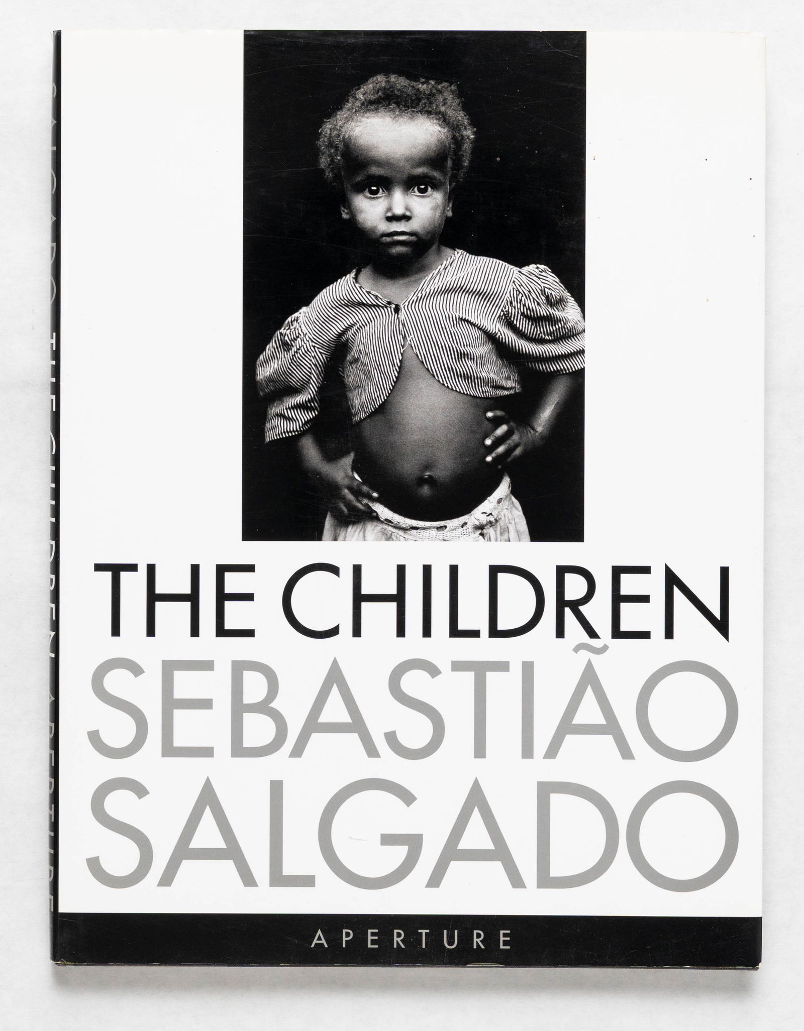 Sebastiao Salgado, The Children [SIGNED 2000 1ST EDITION - FINE]: SIGNED COPY - Aperture, 2000. Hardcover in pictorial dust jacket. First Edition. 12 x 9 inches. 111 pages with nearly 100 portraits of migrant, refugee, and displaced children under the age of fifteen