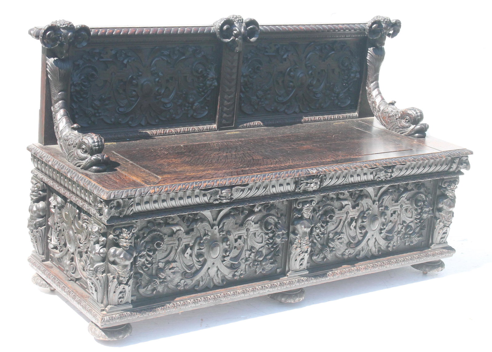highly carved Victorian oak hall seat with ram's head: highly carved Victorian oak hall seat with ram's head crest, dolphin arms, windblowers, and satyr carvings - 60" wide, 22" deep, 37" tall