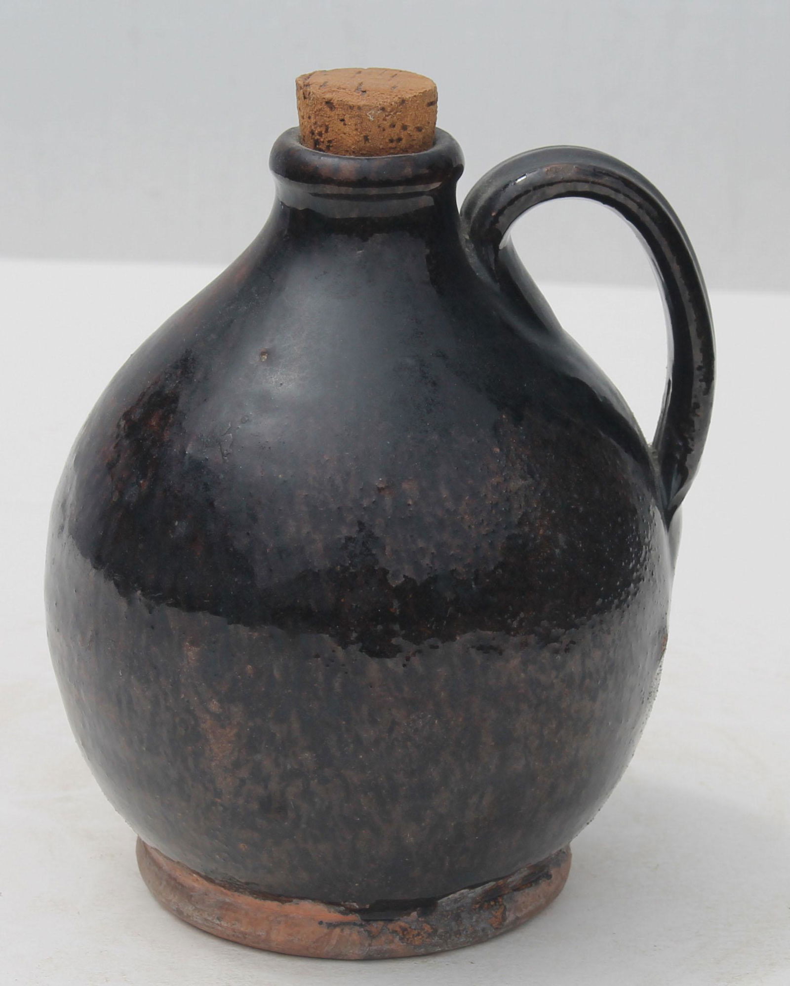 19thC redware jug in speckled glaze w cork - touch of: 19thC redware jug in speckled glaze w cork - touch of glaze loss on back under handle - 5 3/4" tall