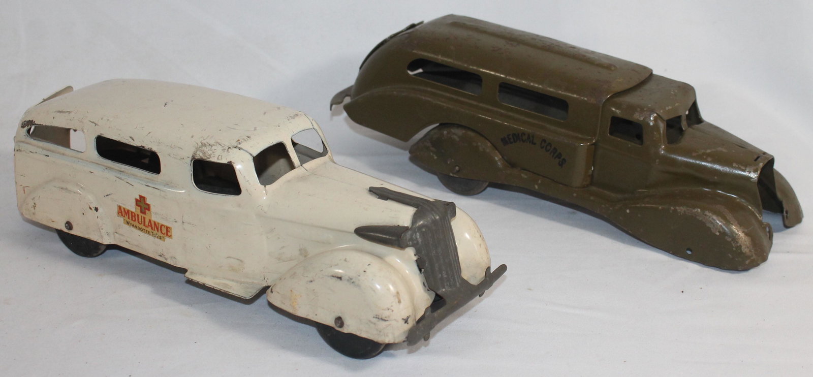 lot of 2 Wyandotte pressed metal vehicles incl an: lot of 2 Wyandotte pressed metal vehicles incl an ambulance and an as found army truck - missing front wheels & fender - 11" long