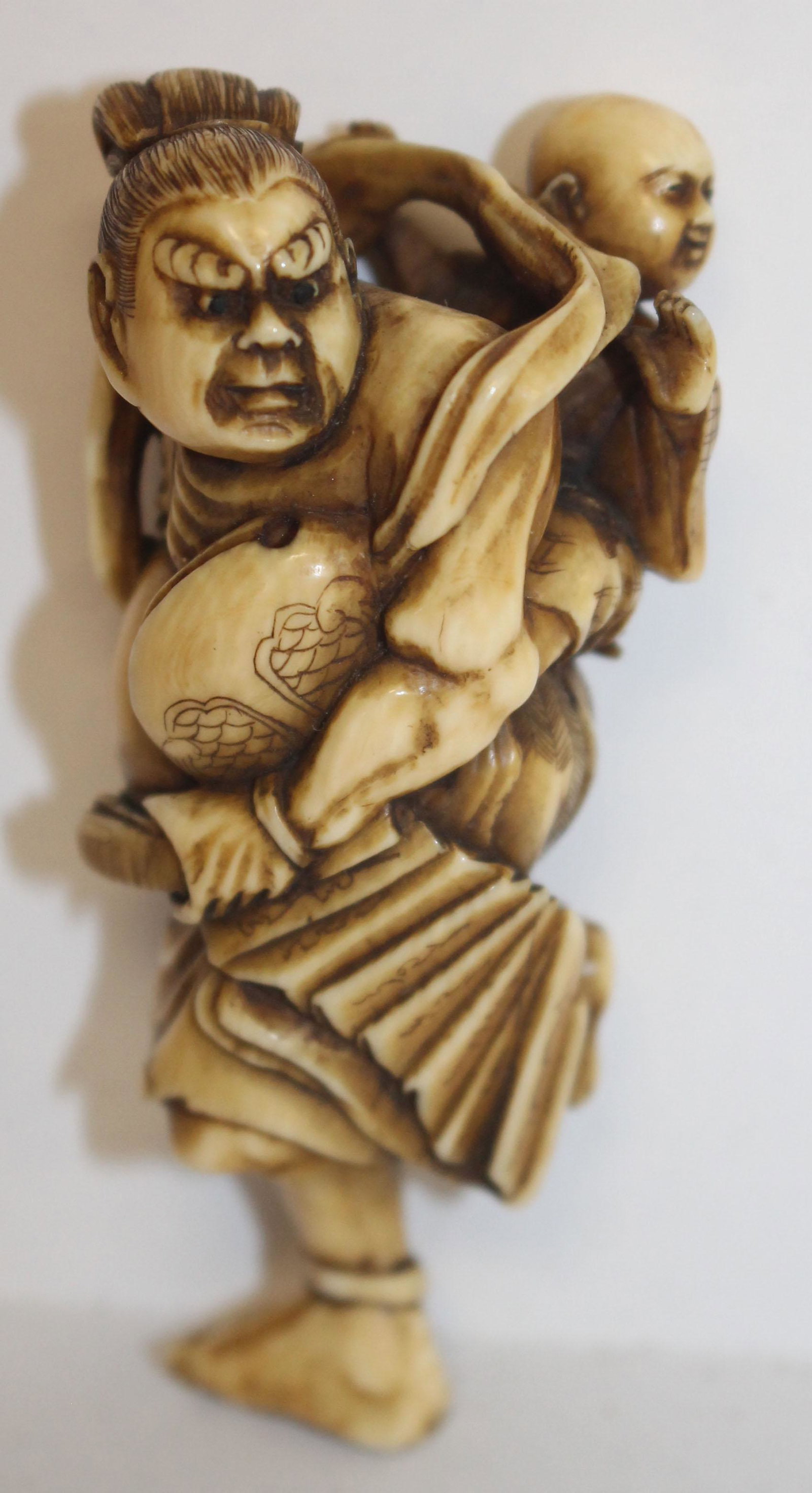 Japanese carved netsuke of figure w Buddha on his back: Japanese carved netsuke of figure w Buddha on his back