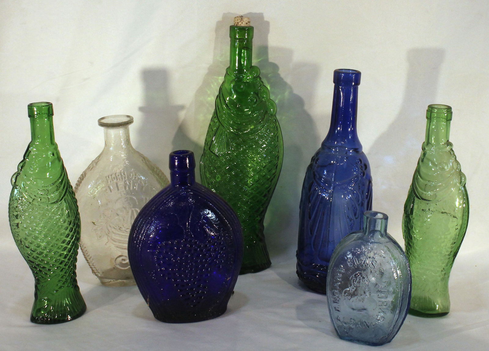 Lot of 7 bottles incl cobalt, light blue & clear glass flasks plus green & cobalt fish form - 6"-12: Lot of 7 bottles incl cobalt, light blue & clear glass flasks plus green & cobalt fish form - 6"-12 3/4" tall