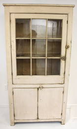 early 19thC cupboard w glazed upper door over 2 lower doors in cream paint (Provenance: ex Jimmie