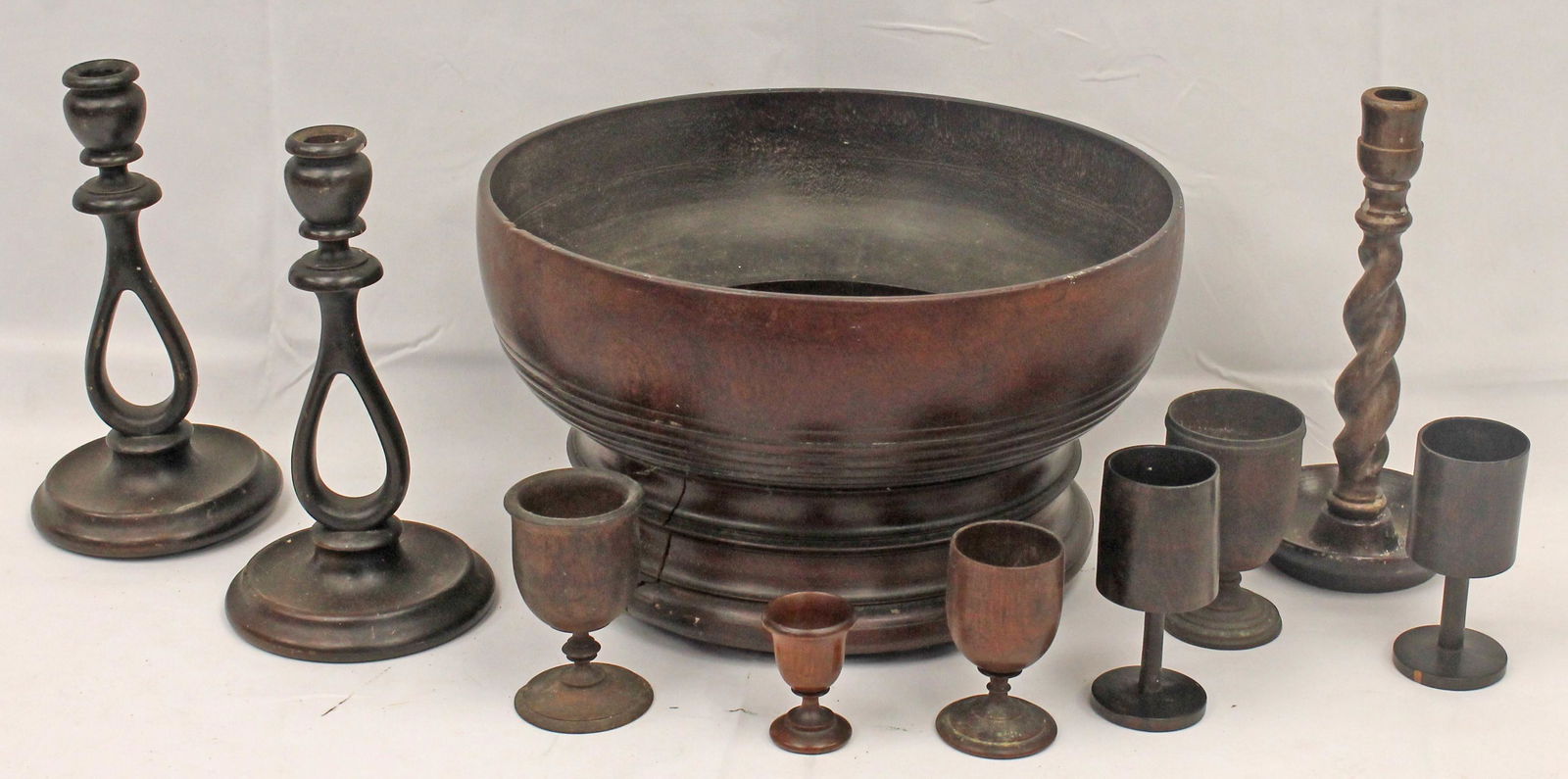 Lot of treen incl large carved wooden bowl 8 1/4" tall x 14" diam; 6 cups 2 3/4" - 5", & 3: Lot of treen incl large carved wooden bowl 8 1/4" tall x 14" diam; 6 cups 2 3/4" - 5", & 3 candlesticks incl a pair 10 1/2" tall - Matthew Mead collection