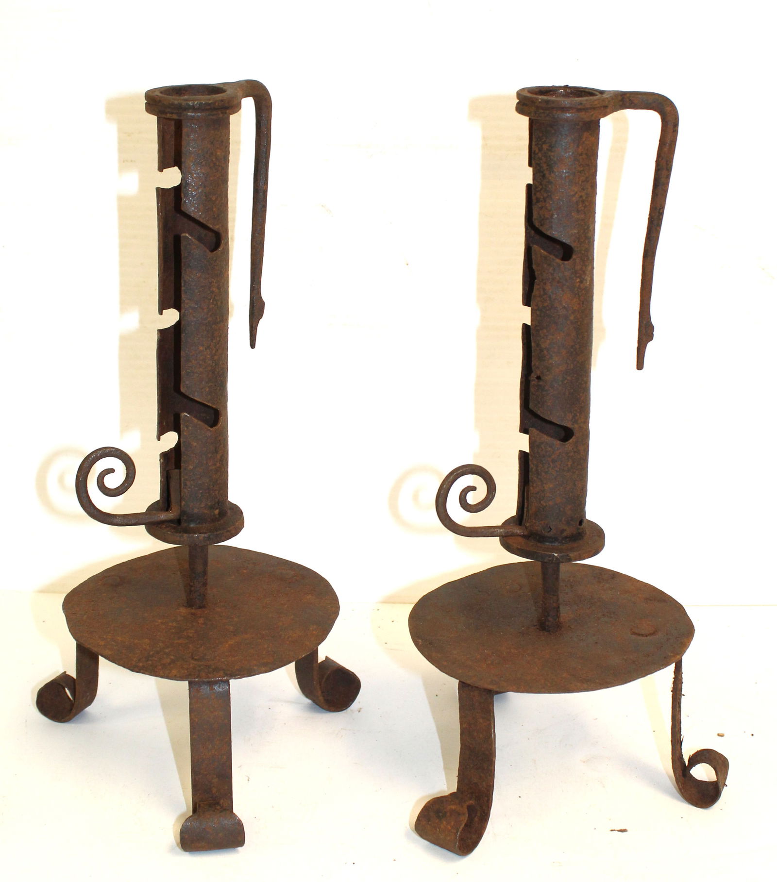 Pair of wrought iron push up candlesticks on tripod feet: Pair of wrought iron push up candlesticks on tripod feet