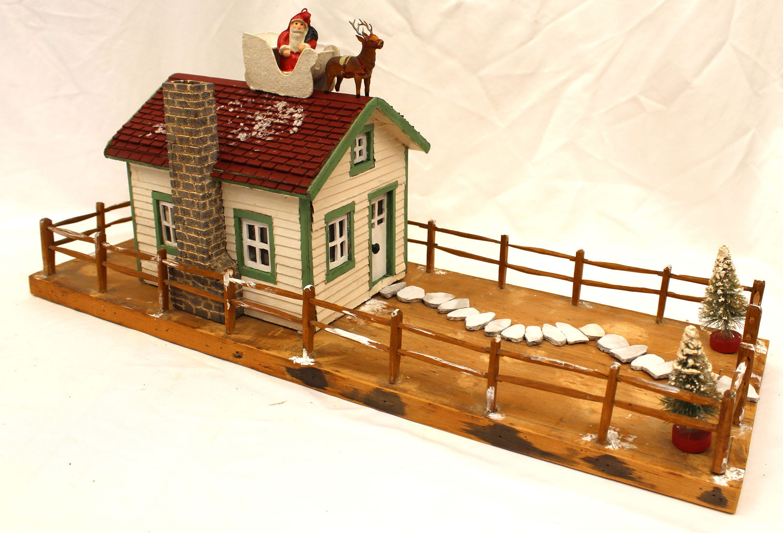 German house w fence around snow covered yard w bottle brush trees & Santa in sleigh w reindeer on (1 of 8)