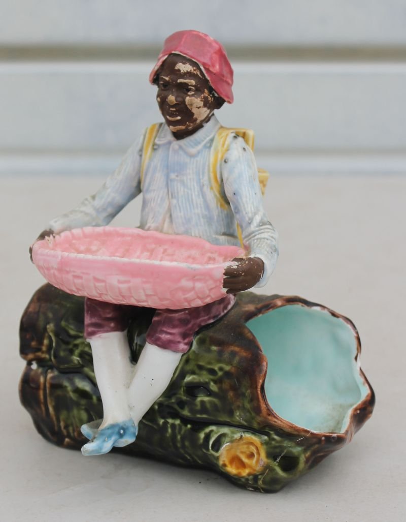 Antique Majolica African American figural match safe w: Antique Majolica African American figural match safe w striker depicting a man w back pack basket & basket on his lap