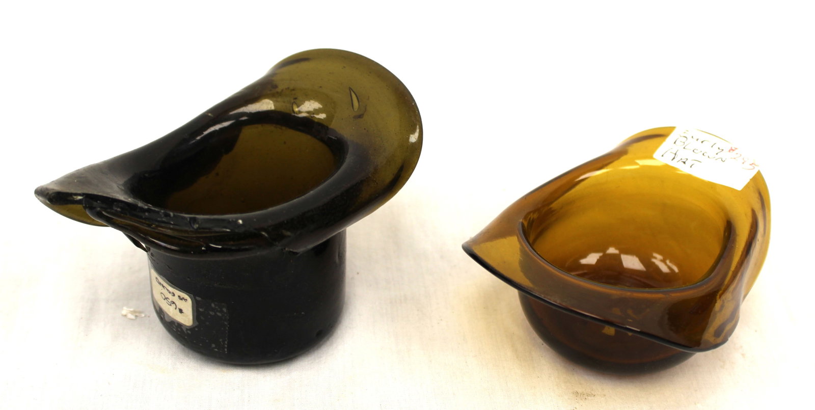 Lot of 2 early amber & green glass hats - as found - 1 1/2" tall x 4 1/4"x3 1/2" & 3 1/2" tall x 4: Lot of 2 early amber & green glass hats - as found - 1 1/2" tall x 4 1/4"x3 1/2" & 3 1/2" tall x 4 1/2"x3"