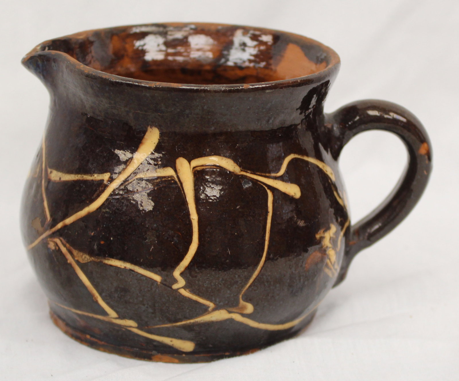 Antique redware creamer/pitcher w slip dec - 4" tall: Antique redware creamer/pitcher w slip dec - 4" tall