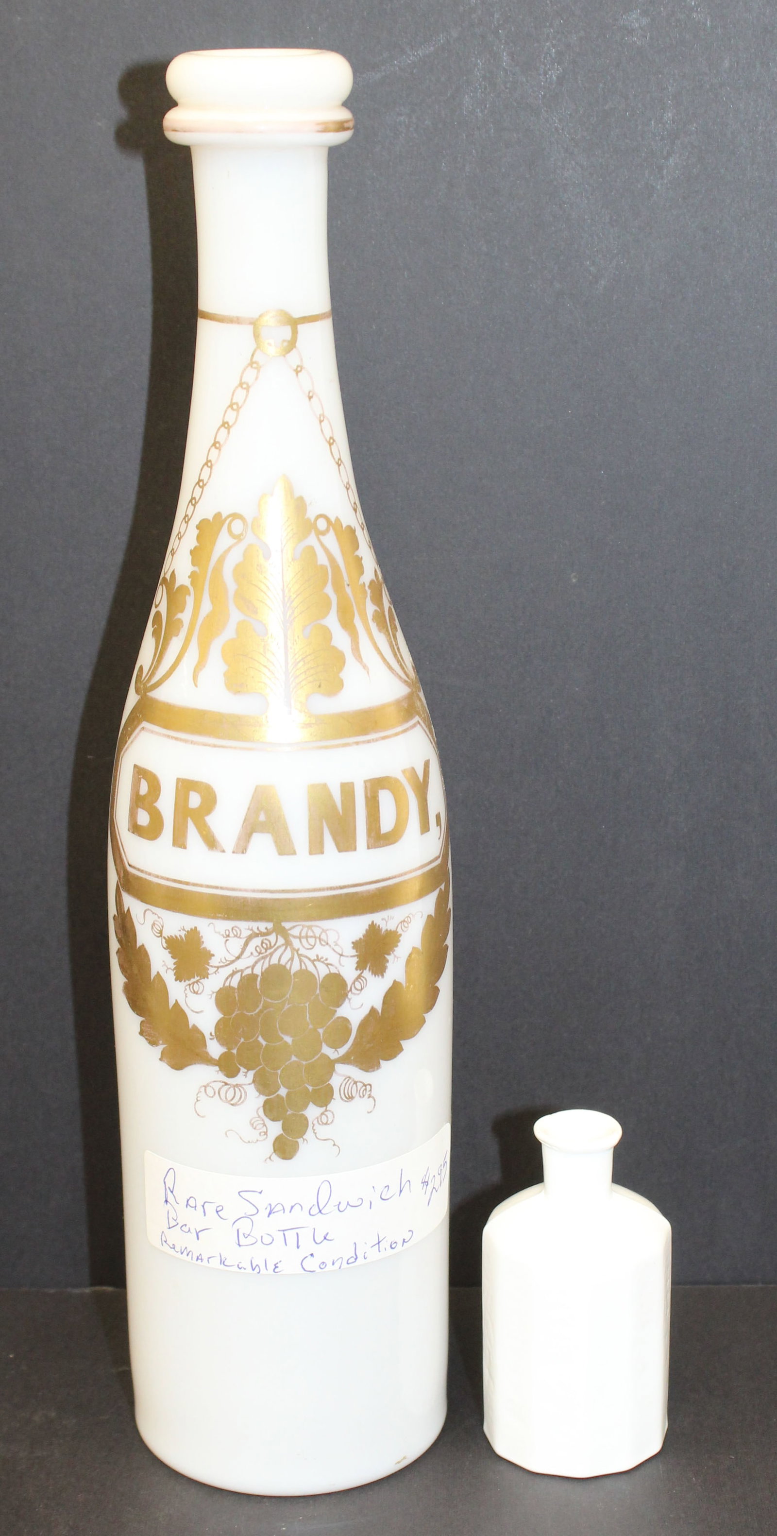 Lot of 2 early white glass bottles incl tall bar bottle w gold decoration lettering "Brandy" & a (1 of 8)