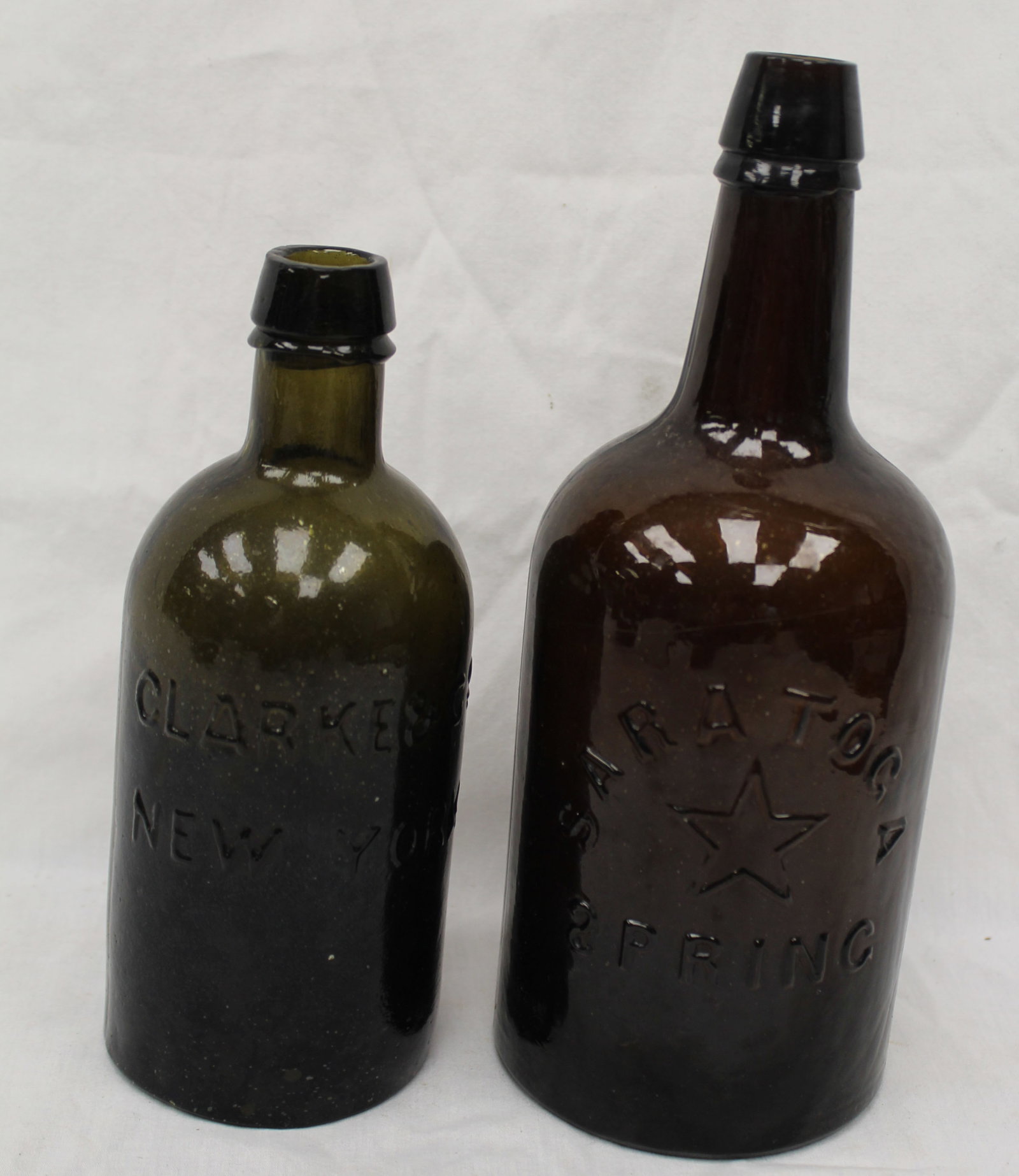 Lot of 2 early NY glass bottles in amber & green - Clarke's & Saratoga - 9 1/4" & 12 1/2" tall: Lot of 2 early NY glass bottles in amber & green - Clarke's & Saratoga - 9 1/4" & 12 1/2" tall