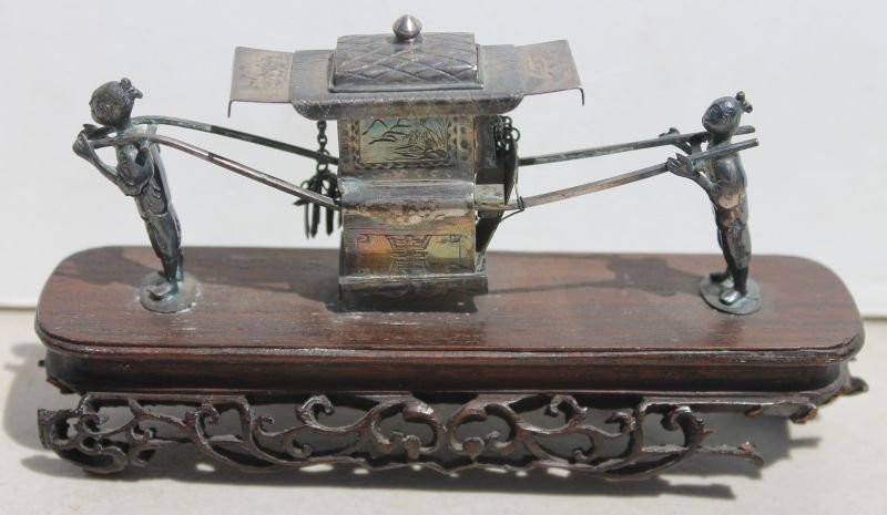 Chinese silver sedan chair carried by 2 figures on: Chinese silver sedan chair carried by 2 figures on carved rosewood or teak base - 5 1/2" long x 3 1/4" tall (some filigree missing from base)