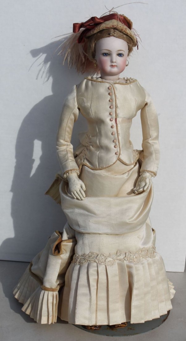 ca 1870's French Fashion doll w bisque swivel head on: ca 1870's French Fashion doll w bisque swivel head on bisque shoulder plate incised "4" at nape, blue threaded glass eyes & beautifully dressed in ivory satin gown w old brown leather boots, gold earr