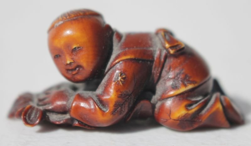 carved & stained Netsuke figure of a child on hands & (1 of 3)
