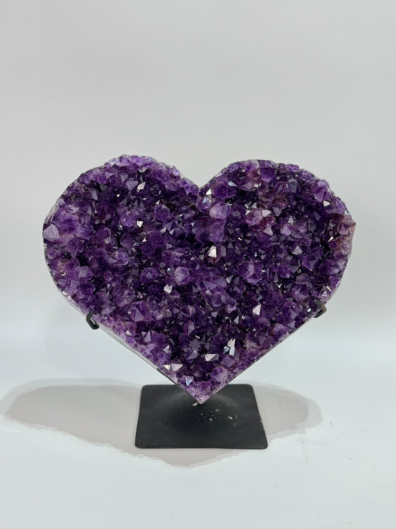 Dark Purple Amethyst Heart on Stand: Dark purple amethyst heart cluster with polished edges on black metal stand. 11” x 12.25” x 7”. 11 pounds, 8 ounces.