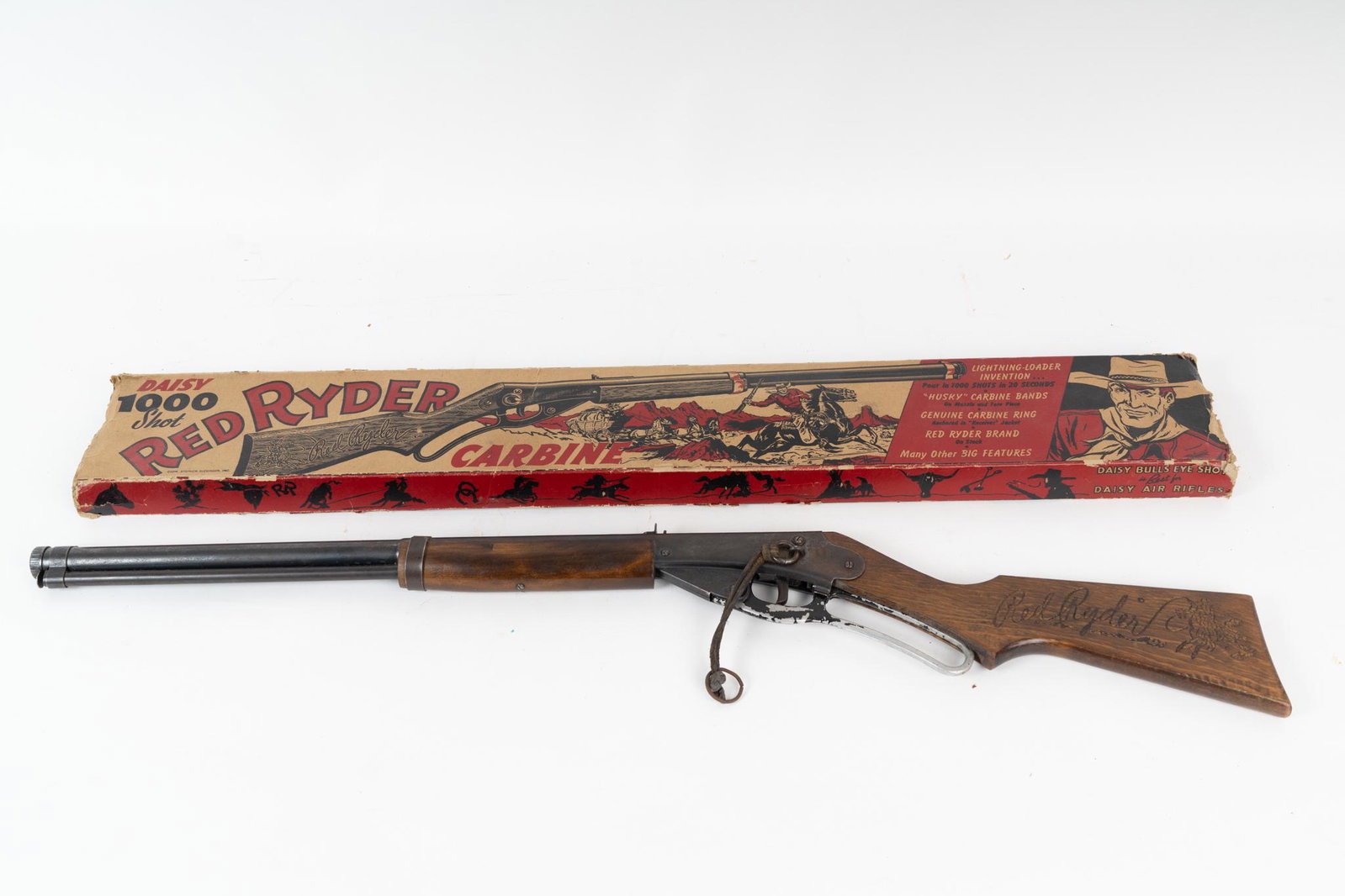 Vintage Daisy Red Ryder Carbine BB Gun with Original Box.: This is the Lightning Loader 1000 shot. The toy gun has wear throughout and with some paint loss and wood bruising. Box is missing both end flaps, but has bright color.