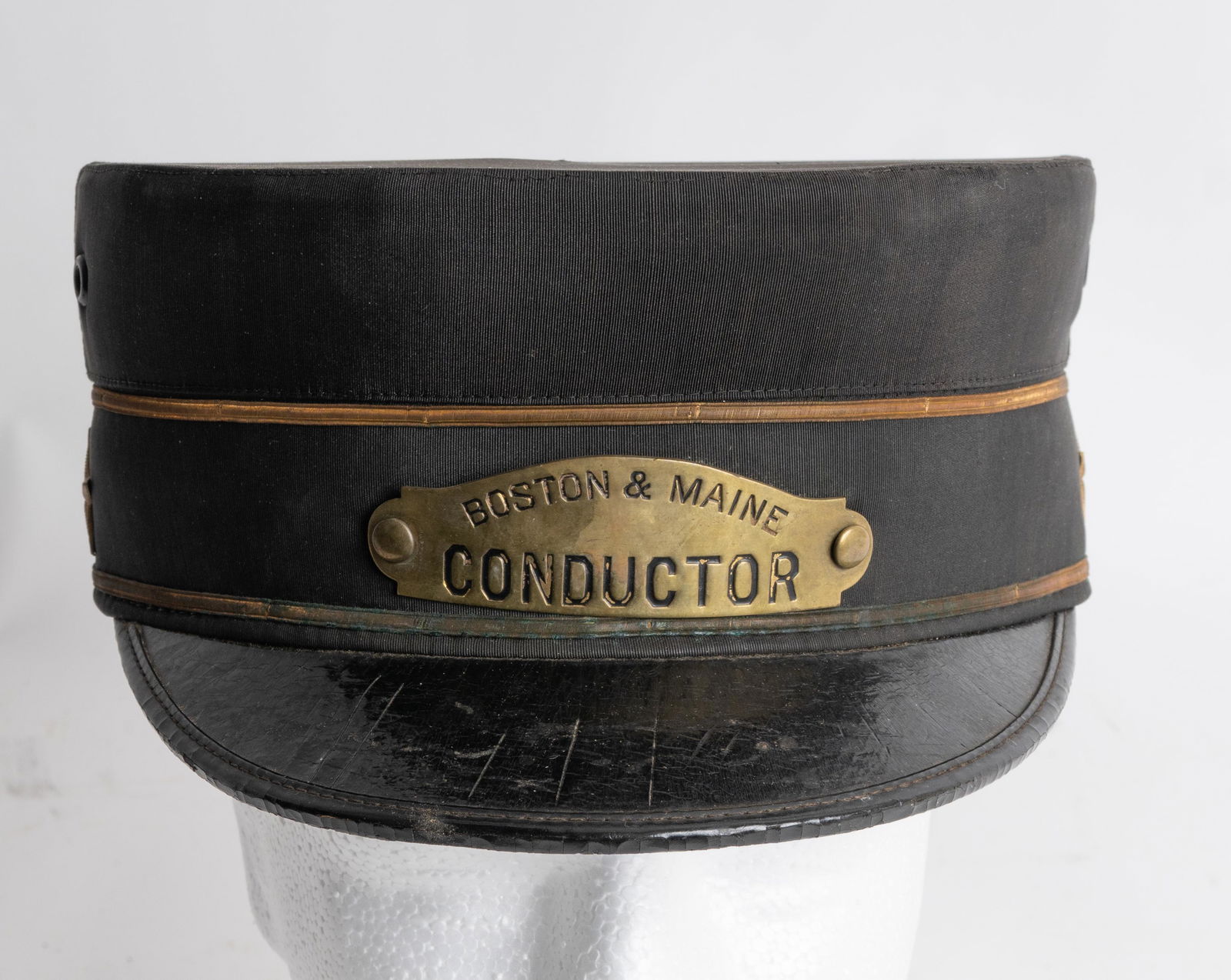 Late 19th-C - 20th-C Boston & Maine Conductor Cap.: This hat has stars on each side with a front brass plate "Boston & Maine / Conductor". Made by "M. Linsky & Bros. 1 Washington ST.Boston, Mass" Size 7-1/4. Black silk fabric with Gold cord and a Japan
