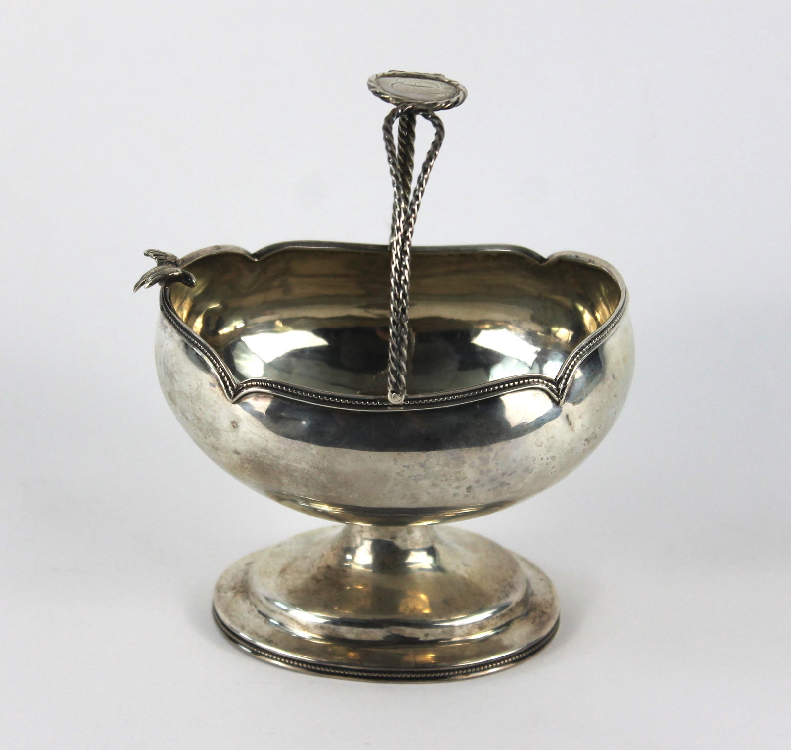 John Cook Sterling Silver Sweet Meats Berry Basket: Hand wrought sterling silver basket with rope style handle and figural perched bird on a beaded rim. Weight as sits 6.13ozt. Approx. 6 1/4" t x 5" w x 3 1/2" d. From the collection of an Upton, Massac