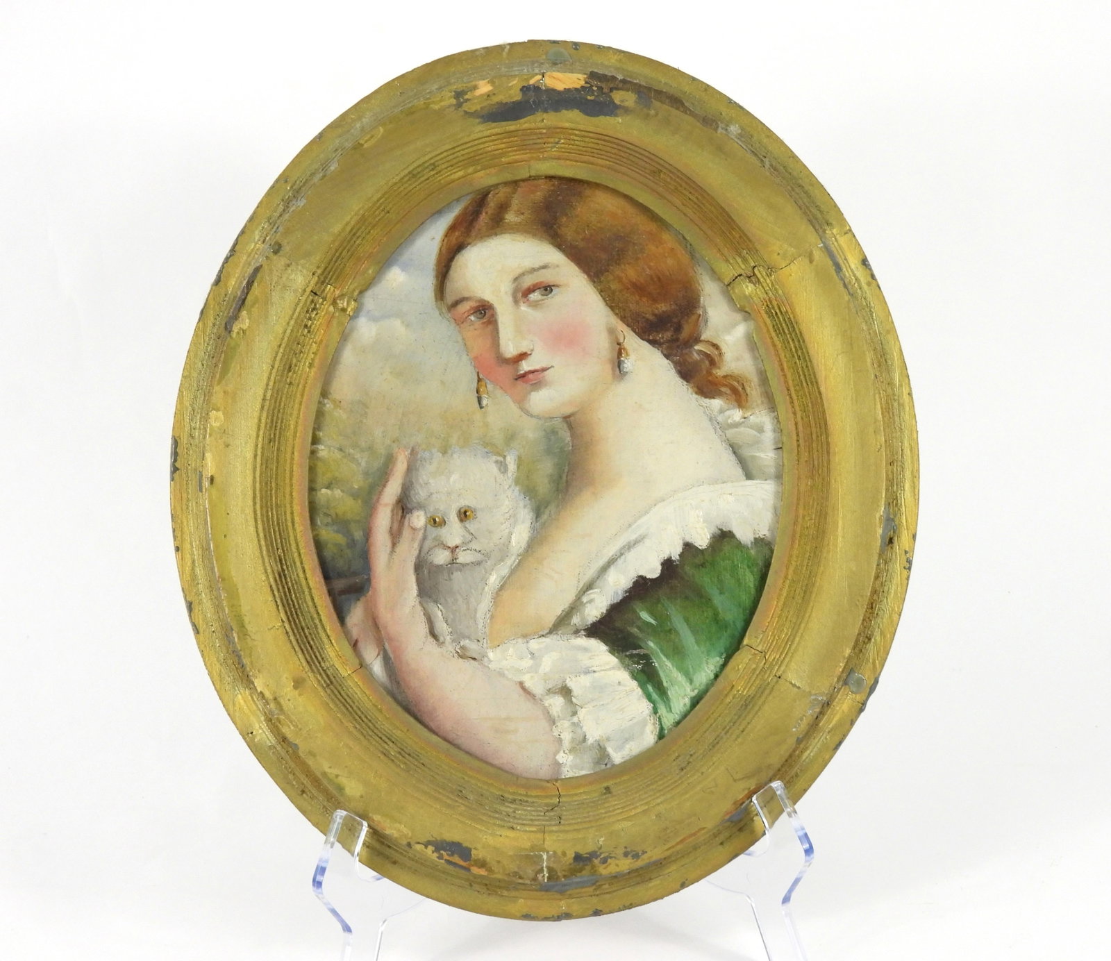 Folk Art Woman Holding A Cat Painting: 19th-20th Century. Oval painting depicting a woman dressed in green caressing a white cat. From the collection of a Boston, Massachusetts estate. Frame 14" x 12"