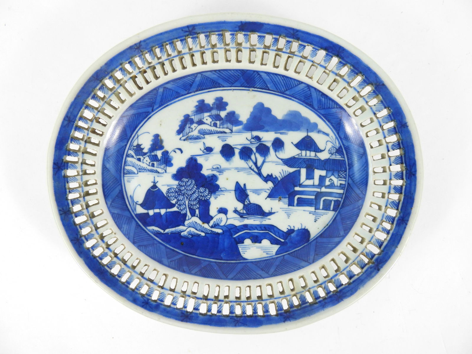Chinese Blue & White Canton Reticulated Plate: China, Early 20th Century. Blue and white oval shaped plate with central landscape scene surrounded by a reticulated rim. From the collection of a Medfield, Massachusetts estate. 8 5/8" x 10 1/4"