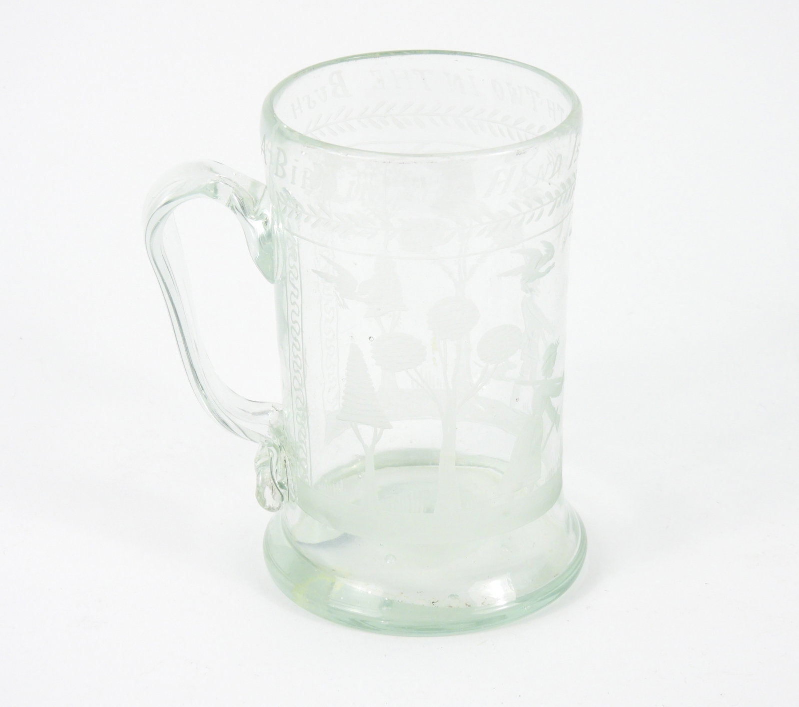 Early Engraved Blown Glass Mug: Glass. Very light Aquamarine color with pontil scar. Engraved outdoor scene figural landscape and birds. "A Bird In The Hand Is Worth Two In The Bush". A private collection.