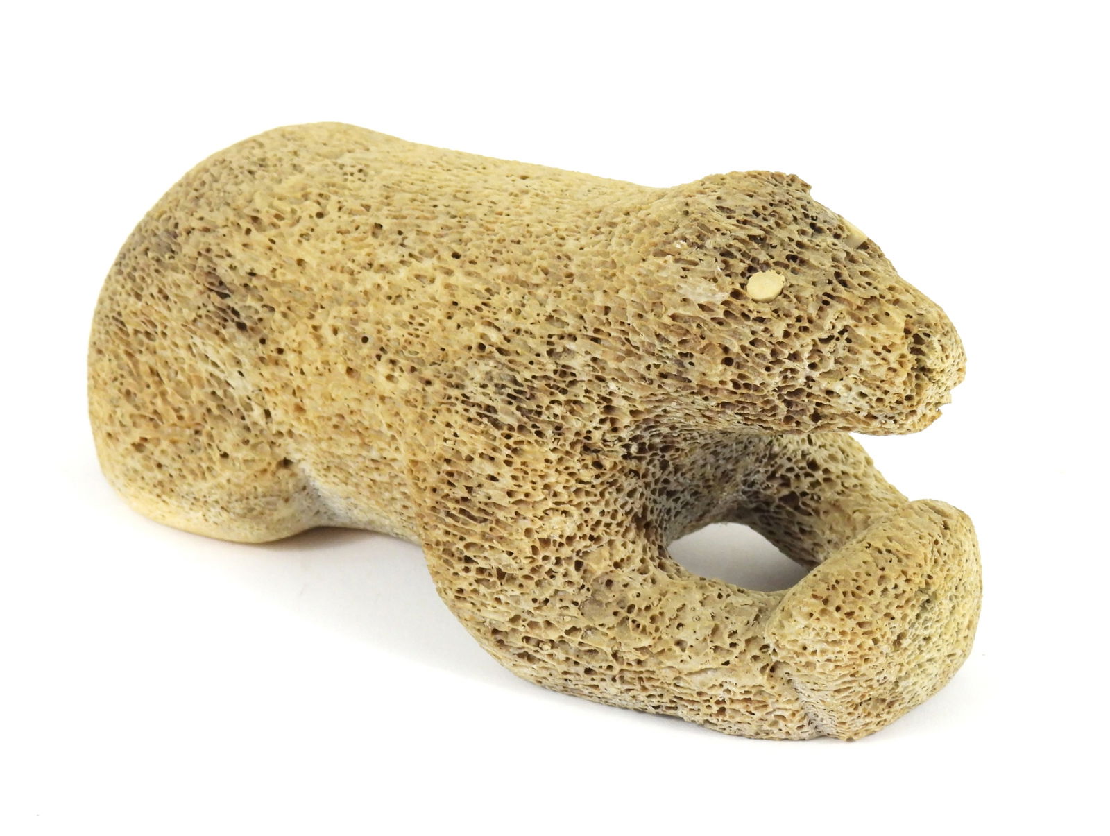 Inuit Carved Petrified Whale Bone Bear Sculpture: North America, 20th Century, Bone. Depicts a polar bear laying down with paws outstretched comprised of porous bone. From the collection of a Princeton, Massachusetts estate.
