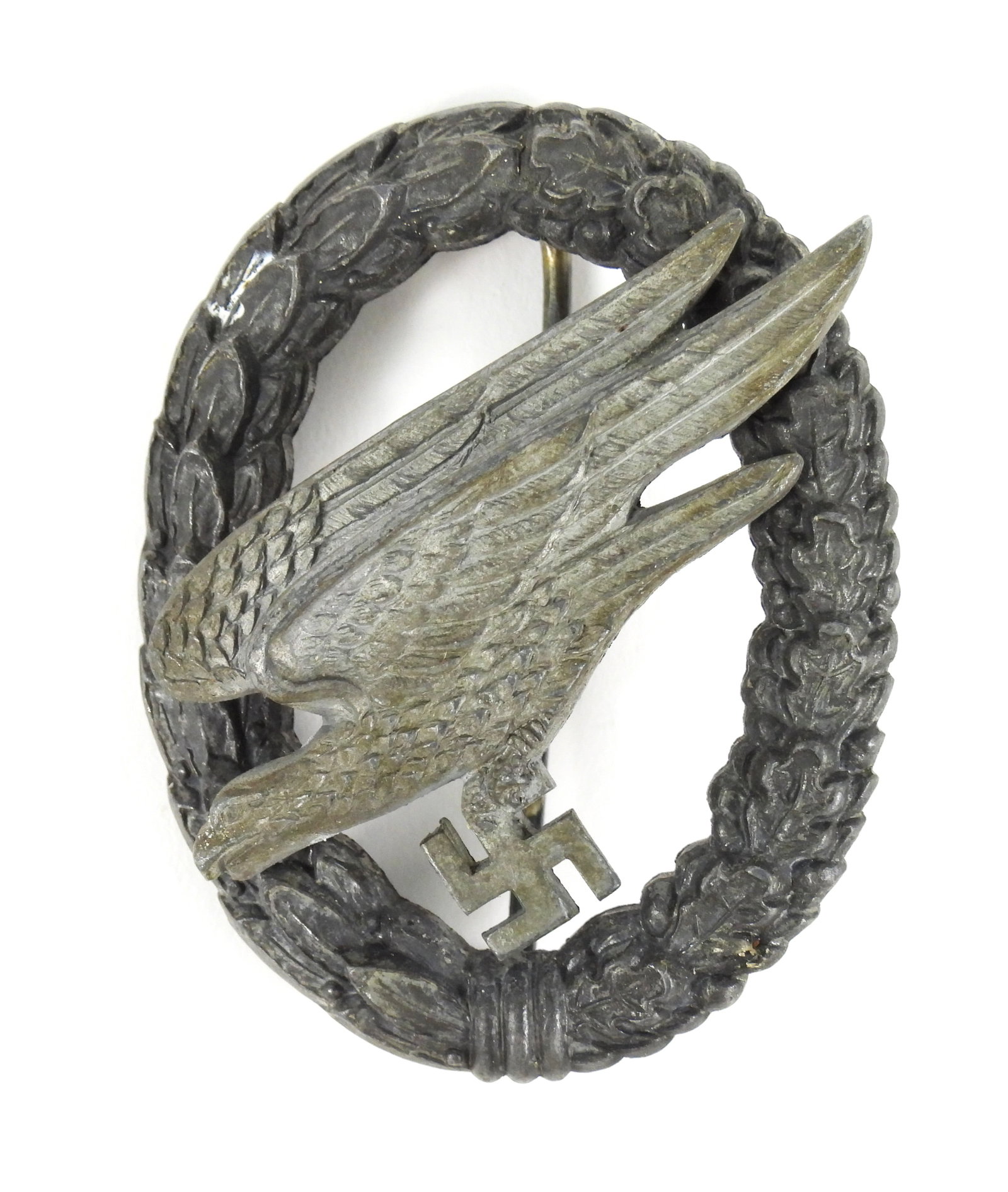 WWII German Paratrooper Badge: Germany. Zinc two-piece medal with a wreath, eagle, and swastika, marked on the back of the eagle "P.MEYBAUER/BERLIN". Overall 2 1/8" x 1 11/16"