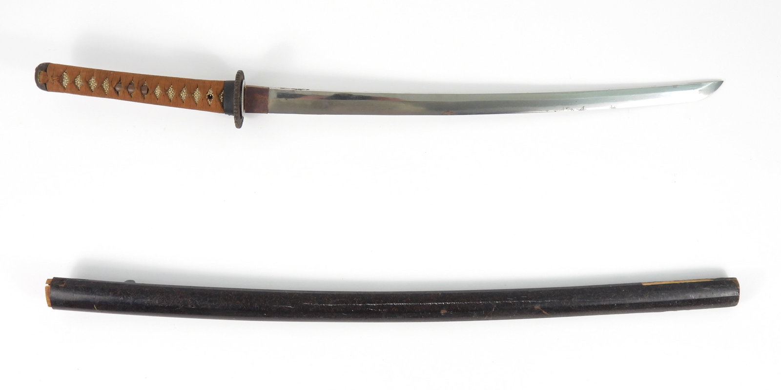 Japanese Wakazashi: Japan. Brown tape-wrapped shagreen grip, iron tsuba with foliate designs, steel blade, and a wooden scabbard. Blade 21", Overall 30"