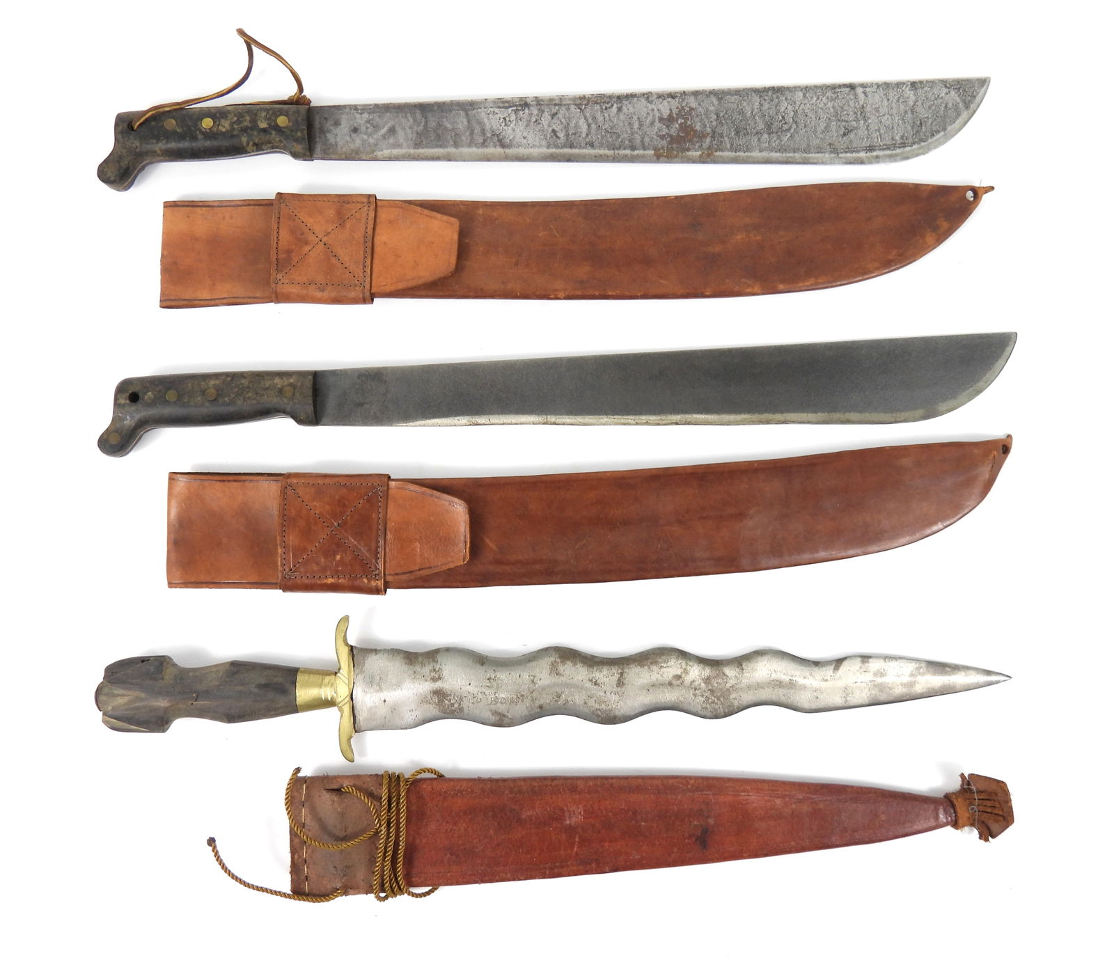 Three WWII-Era Machetes With Sheaths: Mid 20th Century. Two Collins & Company Legitimus with #115 ink stamped on scabbards; and a Negrito Bolo with sheath that is tooled at throat. Largest 23 1/2" longest