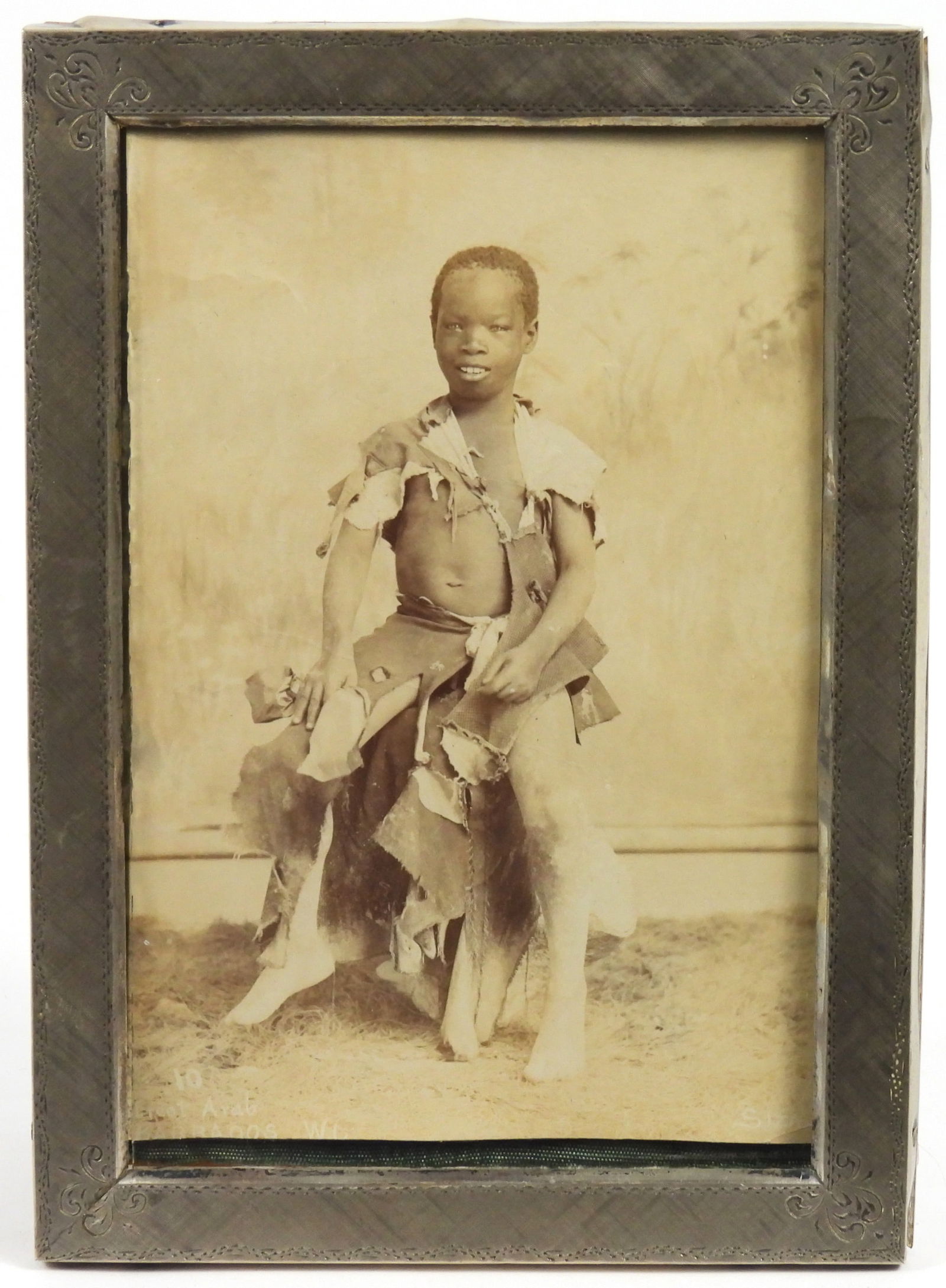 Attr. Manuel Siza Barbados Boy Portrait Photograph: Attr. Manuel Auguste Nunes Siza, Portugal, Barbados, 1841-1919, Photograph. Depicts a seated young black boy wearing patchwork torn clothes smiling to the camera. Manuel Siza and his brother, Julio