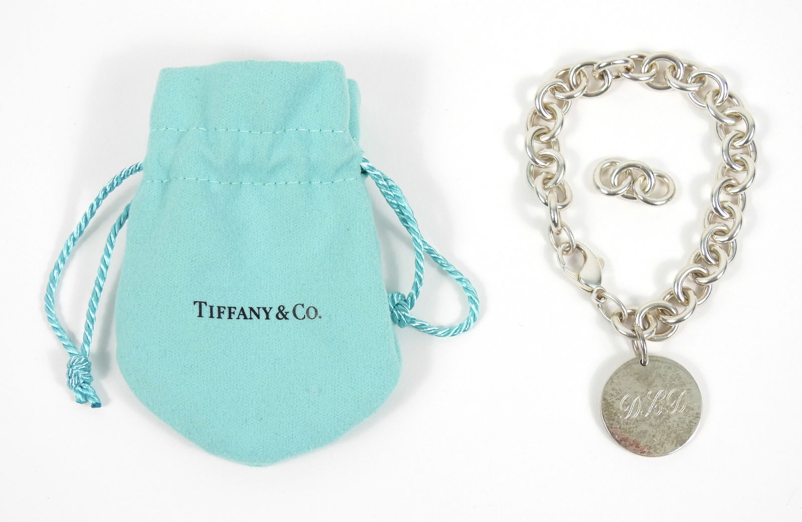 Tiffany & Co Return to Tiffany Charm Bracelet: New York, 20th Century, Sterling silver. Sterling silver chain link bracelet with circle charm marked "Tiffany & Co. 925" over a stylized "W" logo that reads "5 Years." Weight as sits 1.2ozt.