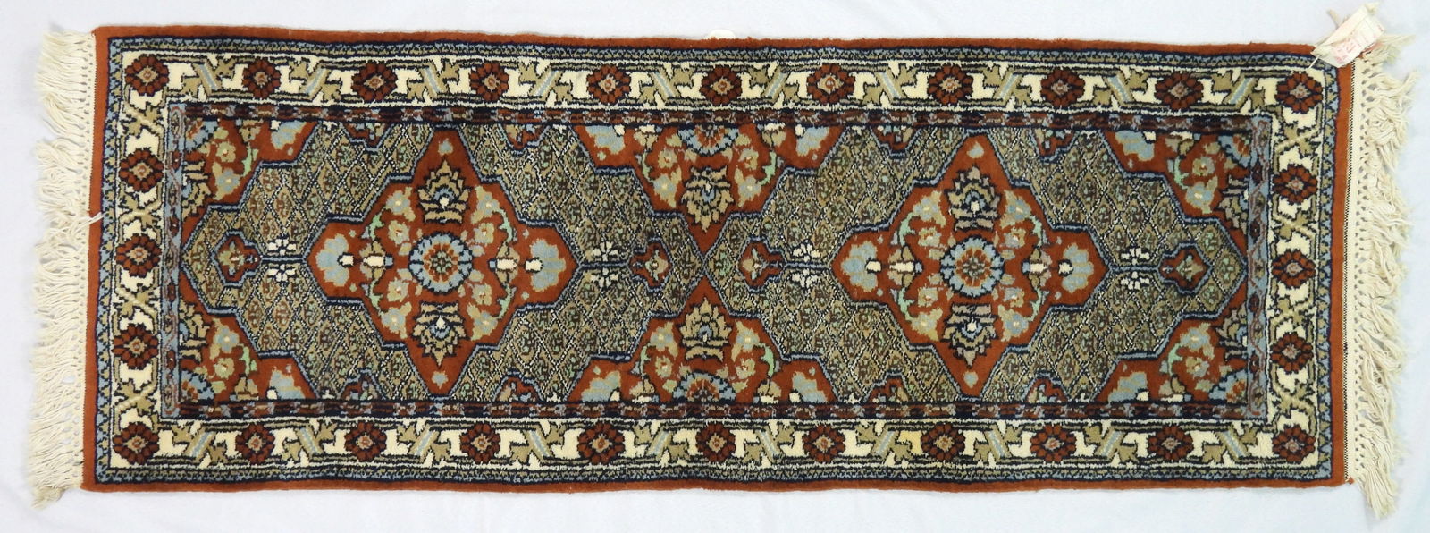 SM Narrow Hand Made Runner Rug: Very good condition, age unknown. Tight weave with bright colors and full pile. Has cleaning, moth repellant, and deodorizer tag still affixed. Approx. 18 1/2" x 56"