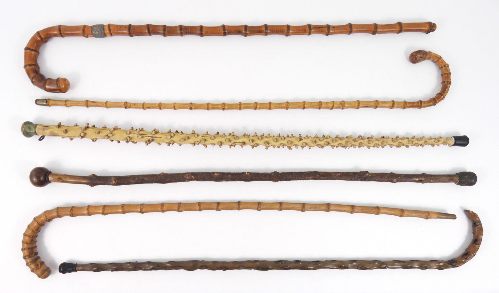 6PC Assorted Antique Canes: Includes six wood and bamboo canes, one bamboo cane is stamped "Howell Of London" and has a woven band that appears to be silver below the hook handle. Longest 37", Shortest 34"