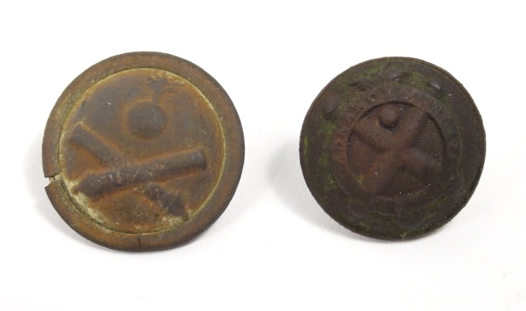 Two Dug US Ordnance Corps Buttons: A coat-size Ordnance Corps button with a flaming bomb over crossed cannons with a "US", with an intact shank and ordnance corps back mark (21.6mm); and a coat-size Ordnance Corps button with crossed c
