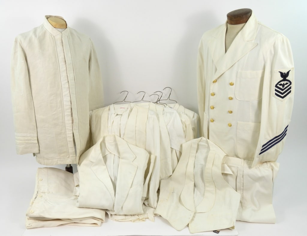Group of US Navy White Summer Dress Uniforms: A WWII US Navy white tunic with brass buttons, chief petty officers enlisted pilot insignia, service stripes, and matching trousers; a white twill jacket with plain buttons and trousers; four white