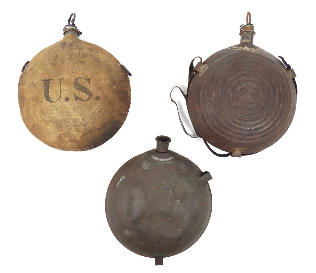 Three 19th Century Military Canteens: A Pattern 1858 smooth side canteen with a bent spout, and one strap tab missing; a "bulls eye" canteen with stopper and remnants of a leather strap; and an Indian War canteen with stopper and cloth